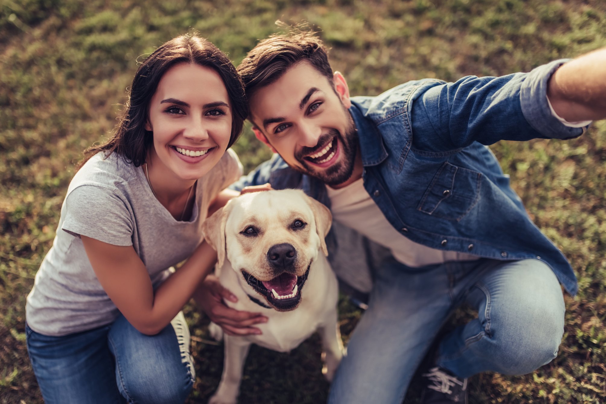 smiling couple with dog taking selfie.
